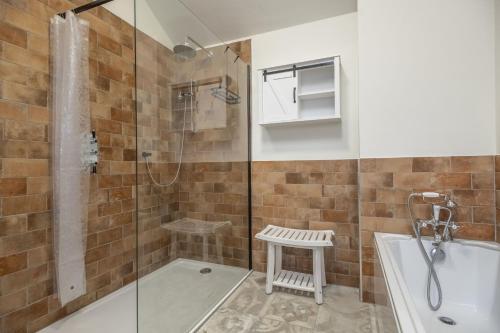 a bathroom with a shower and a tub and a sink at Mill House Cottage in Brancaster
