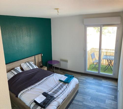 Un dormitorio con una cama con una pared verde. en Appartement 55m² avec vue sur Canigou et Parking, en Rivesaltes