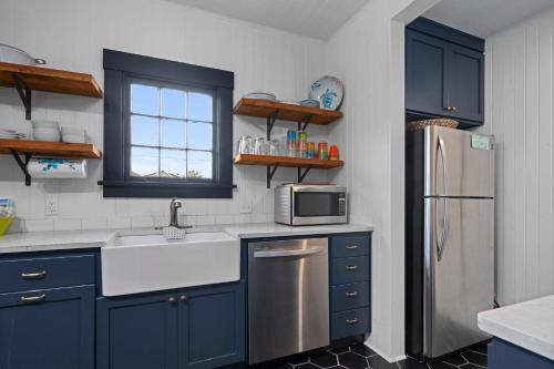 uma cozinha com armários azuis e um frigorífico de aço inoxidável em Oasis By the Sea em Seaside