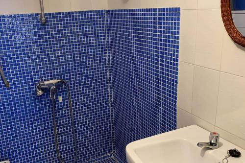 uma casa de banho em azulejos azuis com um lavatório e um chuveiro em Casa Sin Numero, an authentic village house em Comares