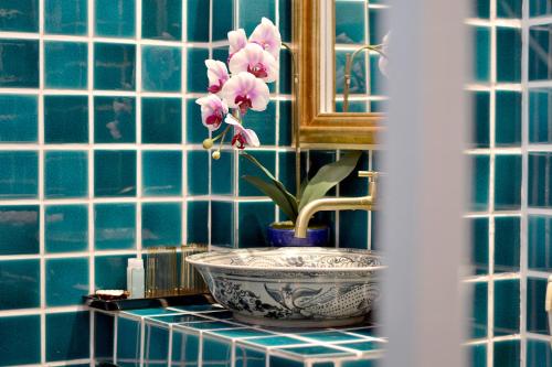 a blue tiled bathroom with a sink and a flower in a bowl at Thai Thai Sukhothai Resort in Sukhothai