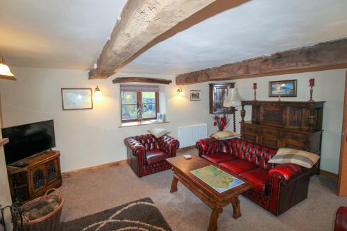 a living room with red leather couches and a tv at Little Barracks, Little Strickland in Little Strickland