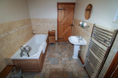 a bathroom with a tub and a sink at Little Barracks, Little Strickland in Little Strickland