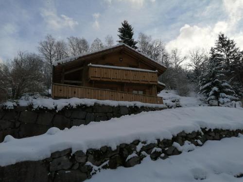a log cabin in the snow with a stone wall at Chalet Typique Vosgien "les Barbotines" in Ventron