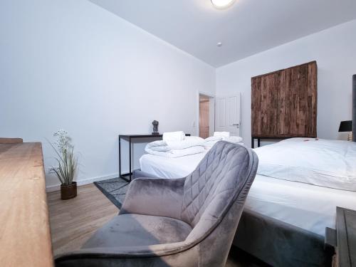 ein Schlafzimmer mit 2 Betten und einem Stuhl darin in der Unterkunft Alpha Apartments in Dortmund