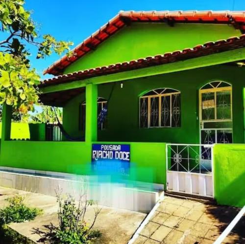 een groen huis met een bord waarop staat dat de terugrit van de gast staat bij Pousada Riacho Doce - Curimataí - Buenópolis - MG in Curumatahy