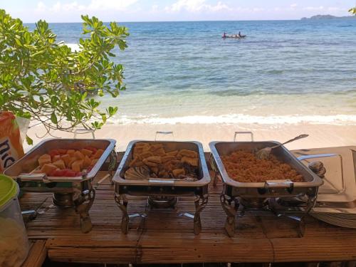 a table with three trays of food on the beach at Lainkalogos glamping in Rabia