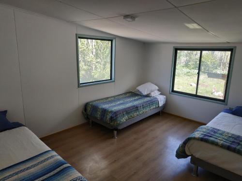 a room with two beds and two windows at Posada de la Luna in Chile Chico