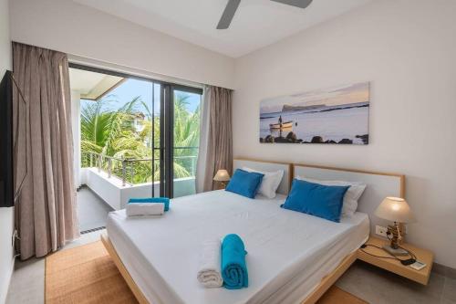 a bedroom with a large bed with blue pillows at Wonderful Mont Choisy flat, huge lagoon pool in Mont Choisy