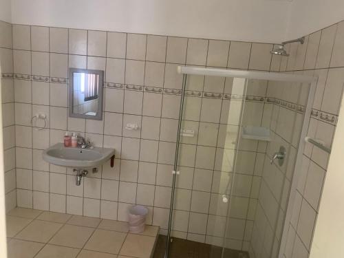 La salle de bains est pourvue d'une douche en verre et d'un lavabo. dans l'établissement Pioneerspark Self Catering, à Windhoek