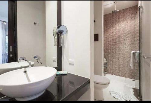 two images of a bathroom with a sink and a toilet at Kata Gardens Apartments in Kata Beach