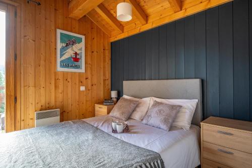 une chambre avec un lit dans une pièce aux murs en bois dans l'établissement Chalet Harvey, aux Gets
