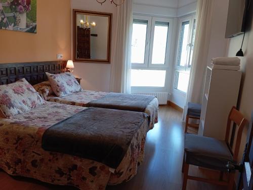 a hotel room with two beds and a chair at Apartamento Peñalabra in Potes