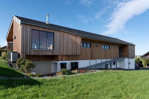 une maison avec une façade en bois sur une pelouse dans l'établissement Fewo Eifel Eichen, à Nideggen