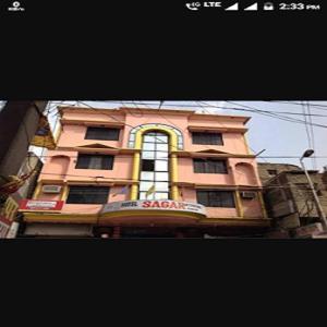 un bâtiment rose avec un panneau devant lui dans l'établissement Hotel Sagar Inn - Bihar, à Samastīpur