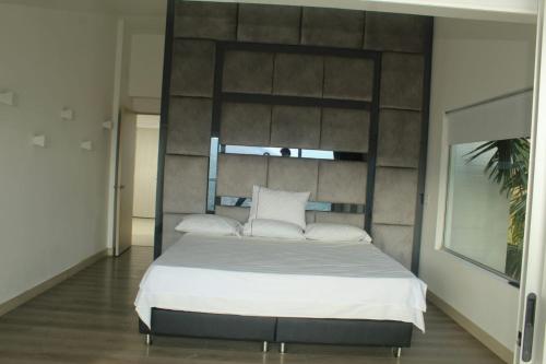 um quarto com uma cama grande com lençóis brancos e almofadas em Mansion 16 em Medellín