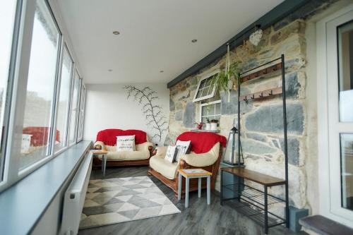 a living room with two chairs and a stone wall at Amazing coastal & sunset views in Eryri (Snowdonia) in Llanllyfni