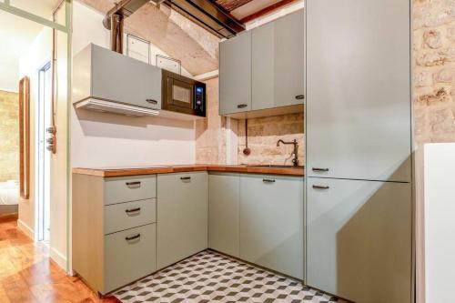 une cuisine avec des armoires blanches et un micro-ondes dans l'établissement Nouveau - Industrial Appartement - 6p - Gym/Sauna, à Paris