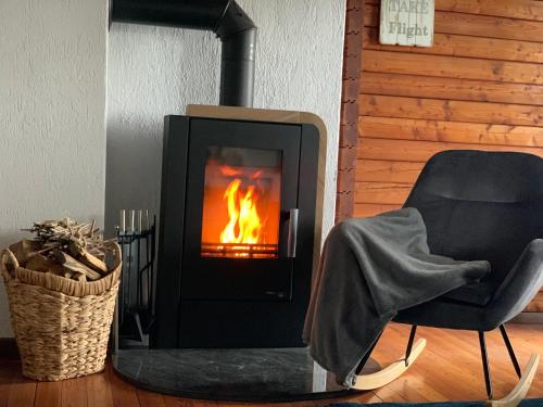 - une cheminée dans une pièce avec une chaise et une chaise dans l'établissement Ferienhaus Auszeit, à Lindenfels