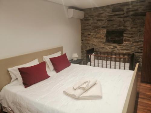 a bedroom with a large white bed with red pillows at Casa de Campo "Quinta do Cadafaz" in Alvarenga