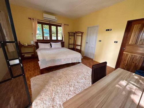 a bedroom with two beds and a table and a window at Beachfront Bungalow lll in Chaloklum