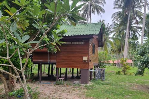 a small wooden house in a field with palm trees at Beachfront Bungalow lll in Chaloklum