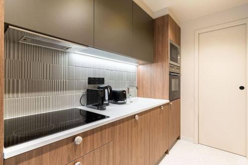 - une cuisine avec des appareils noirs et des armoires en bois dans l'établissement Loft Unique - Opéra / Palais Royal - 2 chambres, à Paris