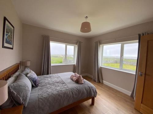 a bedroom with a bed and two windows at Inis Mor, Aran Islands Luxury 5 bedroom with Seaviews 