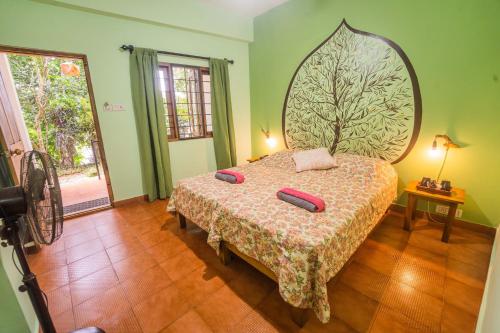 a bedroom with a bed with two pillows on it at Chrissie's Hotel in Thekkady