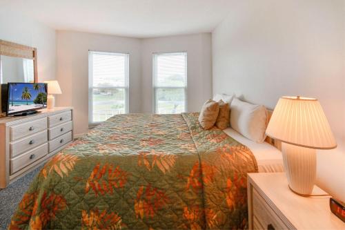 a bedroom with a bed and a dresser with a lamp at Amadeus 6 in St. Pete Beach
