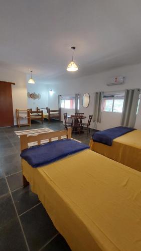 a hotel room with two beds and a table at Pousada Sol do Araçá in São Sebastião