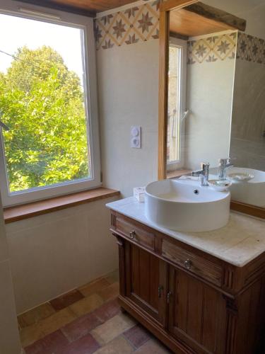 une salle de bain avec un lavabo, un miroir et une fenêtre dans l'établissement Le Hameau des Sources, à Colombier-le-Jeune
