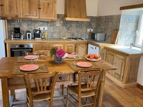 une cuisine avec une table en bois, des chaises et des fruits. dans l'établissement Le Hameau des Sources, à Colombier-le-Jeune