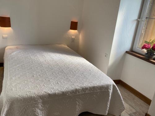 - une petite chambre avec un lit blanc et une fenêtre dans l'établissement Le Hameau des Sources, à Colombier-le-Jeune