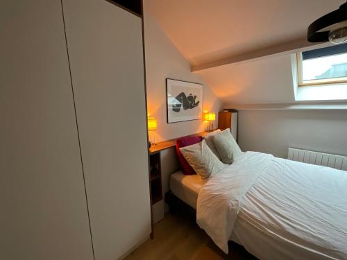 ein kleines Schlafzimmer mit einem Bett und einem Fenster in der Unterkunft Loft de Juliette à Saint-Malo in Saint-Malo