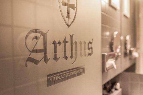 a bathroom with a sign on a wall with a mirror at Hotel Arthus in Aulendorf