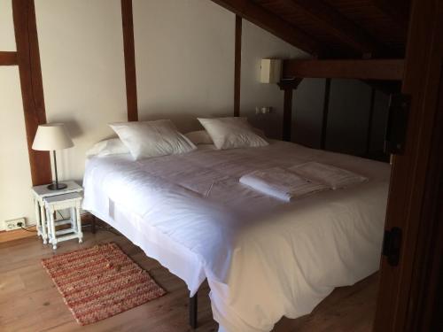sypialnia z dużym łóżkiem z białą pościelą i poduszkami w obiekcie Apartamento loft la casa de las Pajaritas w mieście Pasarón
