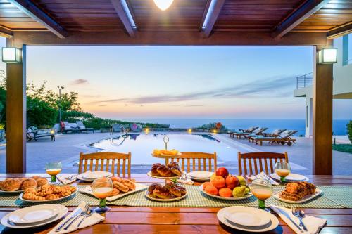 アギア・ペラギアにあるLux Villa Aspalathos with Pool, 700m to Beach, 1km to Restaurantのプールの景色を望むテーブル(食べ物付)