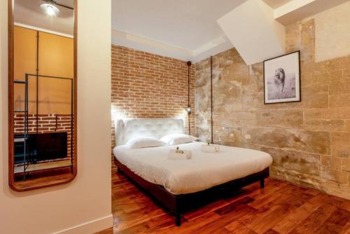 - une chambre aux murs de briques avec un lit et un miroir dans l'établissement NOUVEAU - Loft industriel - 4pp, à Paris