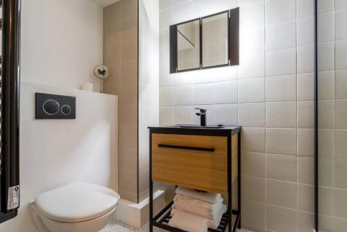 y baño con aseo, lavabo y espejo. en NOUVEAU - Loft industriel - 4pp, en París