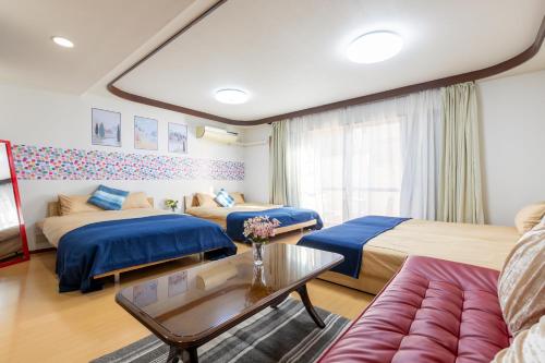 a hotel room with two beds and a couch at Shinjuku Yotsuya House in Tokyo