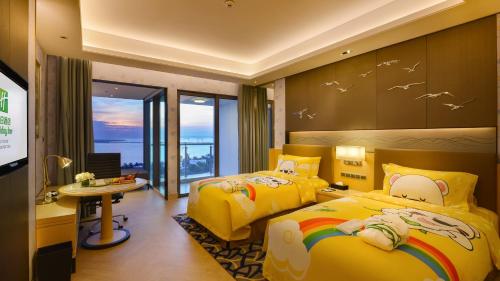 a bedroom with two beds and a desk and a table at Holiday Inn Haikou West Coast, an IHG Hotel in Haikou