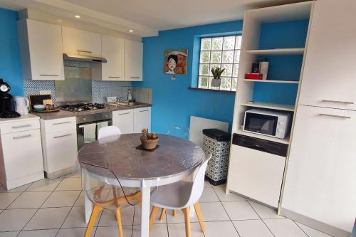eine Küche mit einem Tisch und einer blauen Wand in der Unterkunft duplex cocooning à 10 min à pied du centre ville in Saint-Nabord