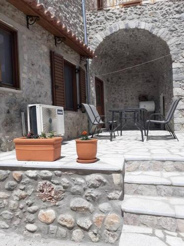un patio al aire libre con mesa y sillas y un edificio de piedra en klisounis house, en Leonidio
