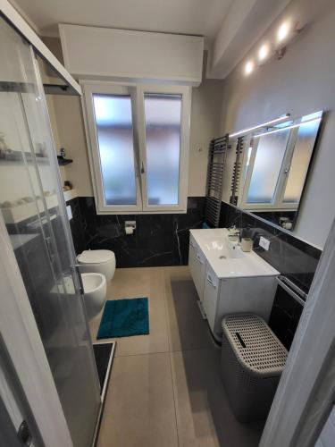 ein Badezimmer mit einem Waschbecken, einem WC und einem Spiegel in der Unterkunft Big Terrace Modena Apartment in Modena
