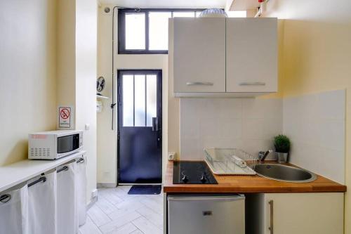 une petite cuisine avec un évier et un micro-ondes dans l'établissement Unique Studio in Marais, à Paris