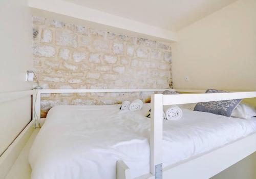 - une chambre avec 2 lits, des draps blancs et des serviettes dans l'établissement Unique Studio in Marais, à Paris