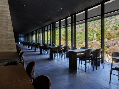 a row of tables and chairs in a room with windows at Unzen Miyazaki Ryokan in Unzen