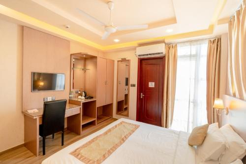 a hotel room with a bed and a desk and a television at Three Inn in Hulhumale