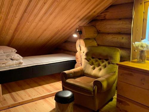 a room with a chair and a bed in a cabin at Ruska 2, Ylläs - Log Cabin with Lake and Fell Scenery in Äkäslompolo